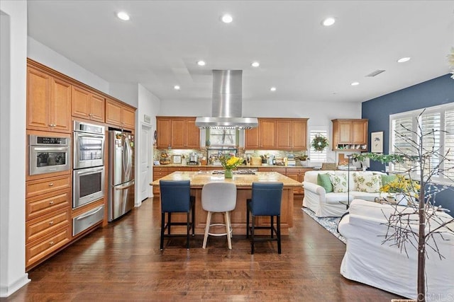 kitchen with island range hood, dark wood-style flooring, stainless steel appliances, a warming drawer, and a center island