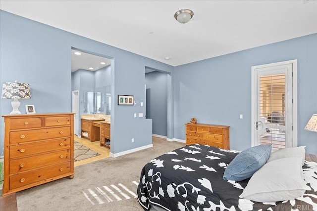 bedroom with light colored carpet, baseboards, and connected bathroom