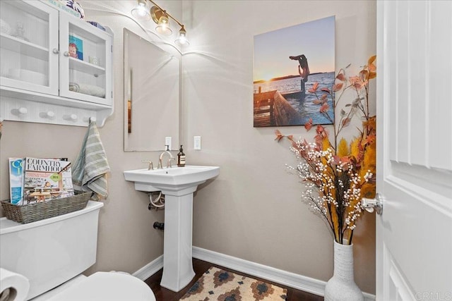 half bathroom featuring toilet, baseboards, and wood finished floors