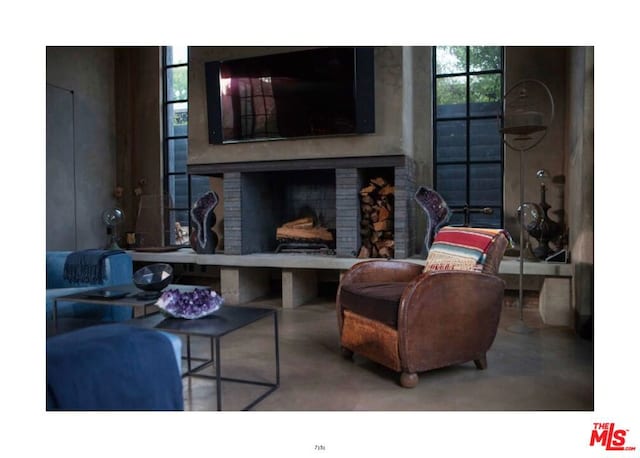 living room featuring a brick fireplace and concrete floors