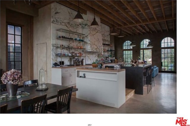 kitchen featuring white cabinetry, high vaulted ceiling, a kitchen island, and beamed ceiling