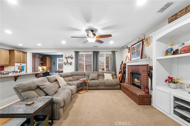 living room featuring ceiling fan, a brick fireplace, and light carpet