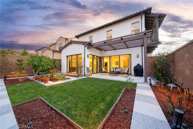 back of property at dusk featuring stucco siding, a fenced backyard, a yard, an outdoor hangout area, and a patio area