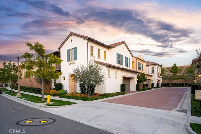 view of front of property with stucco siding, a tiled roof, an attached garage, and decorative driveway