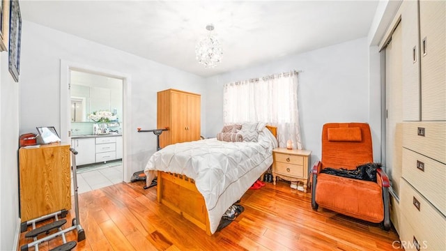 bedroom featuring ensuite bath, light hardwood / wood-style floors, and a notable chandelier