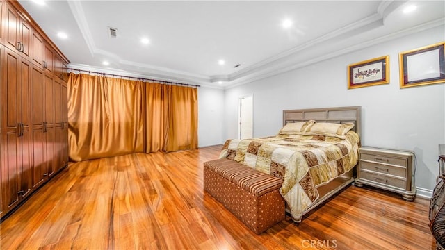 bedroom with a raised ceiling, wood-type flooring, and crown molding