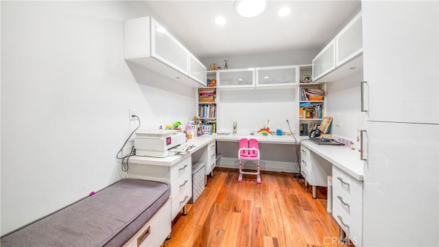 interior space with built in desk, white cabinets, and light wood-type flooring