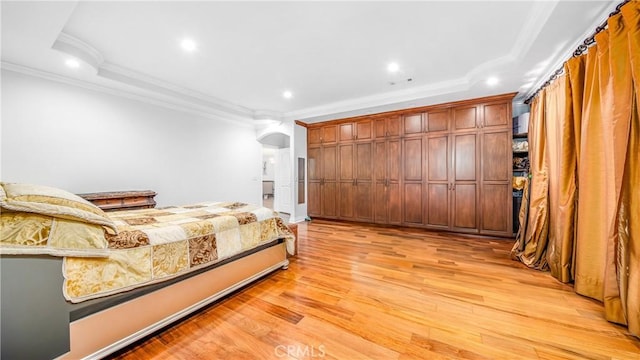 bedroom with crown molding, light hardwood / wood-style flooring, and a raised ceiling