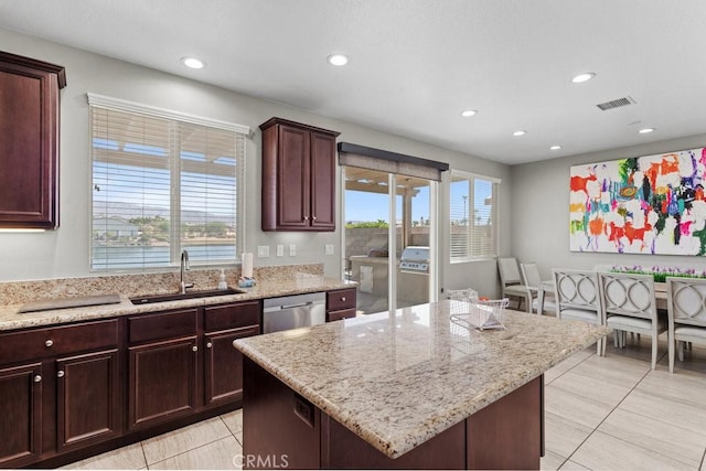 kitchen with light tile patterned flooring, a kitchen island, dishwasher, sink, and light stone counters