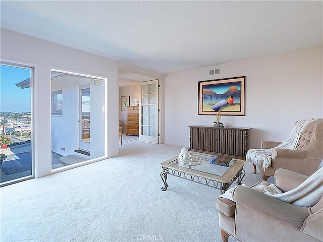 living room featuring carpet, a textured ceiling, and visible vents
