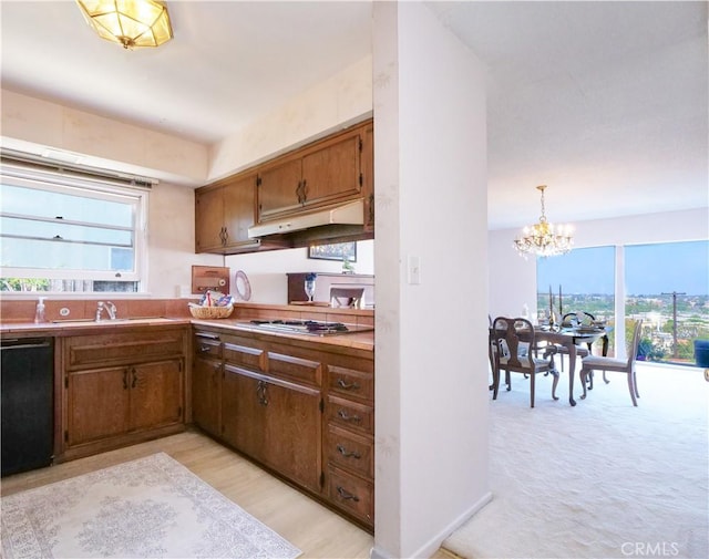 kitchen featuring an inviting chandelier, under cabinet range hood, a sink, stainless steel gas stovetop, and dishwasher