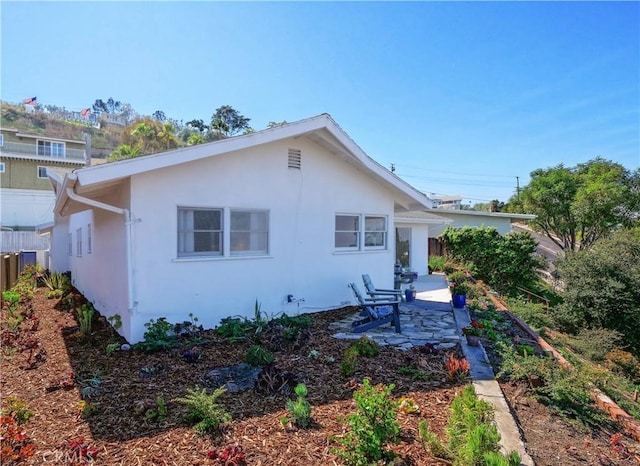 rear view of property featuring fence, stucco siding, and a patio