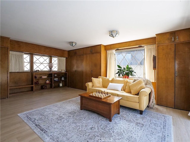 living room featuring a healthy amount of sunlight, wooden walls, and light wood-type flooring