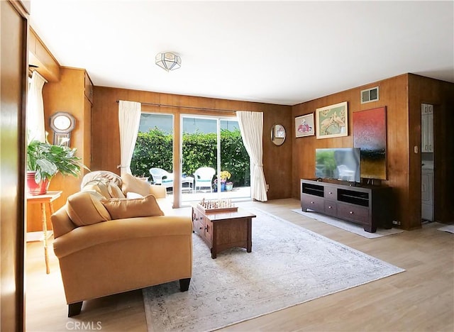 living room featuring wooden walls and light hardwood / wood-style floors