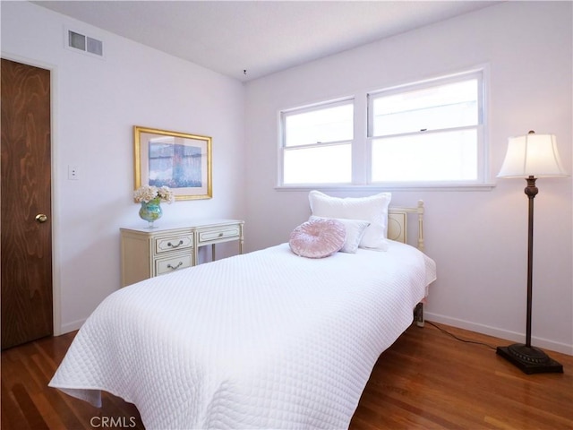 bedroom with wood finished floors, baseboards, and visible vents