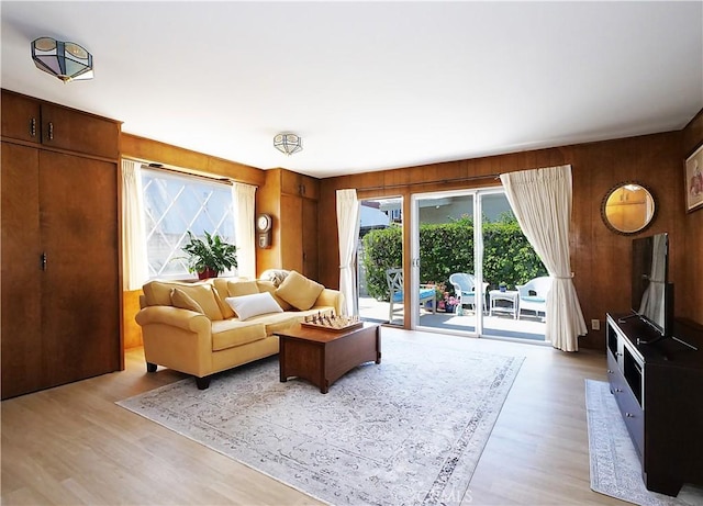 living room featuring light wood-type flooring and wood walls