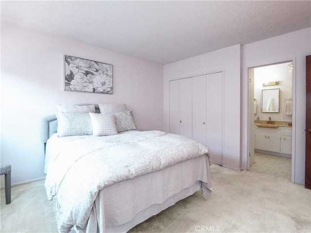 carpeted bedroom featuring sink, ensuite bath, and a closet