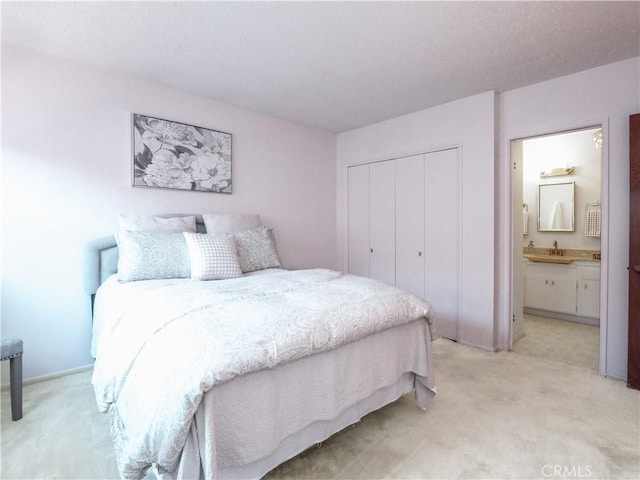 bedroom with a sink, light carpet, connected bathroom, and a closet