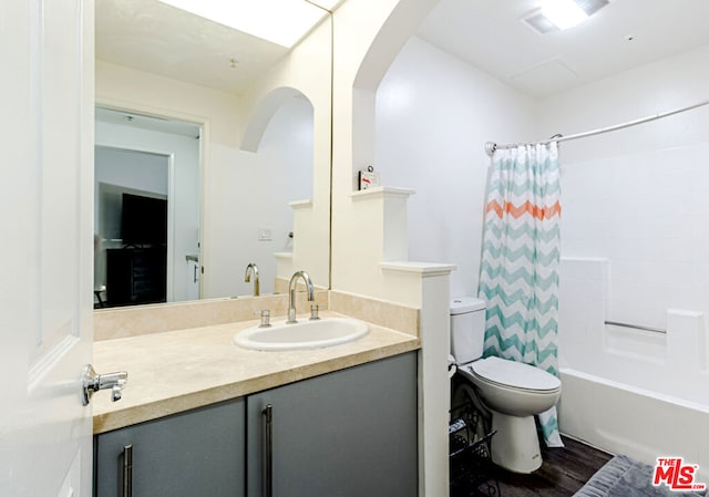 full bathroom with hardwood / wood-style flooring, vanity, shower / tub combo with curtain, and toilet