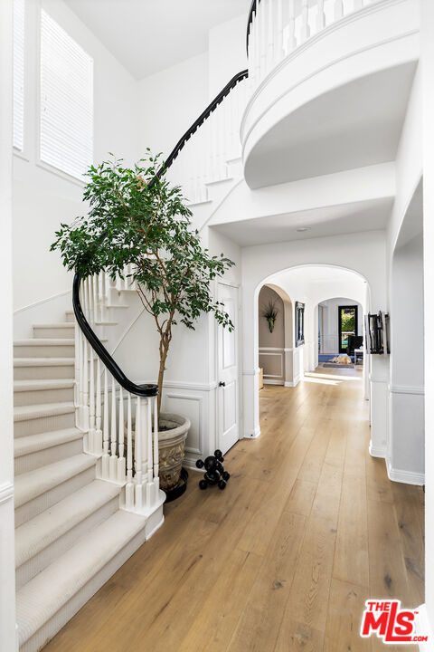 hall with a towering ceiling and wood-type flooring