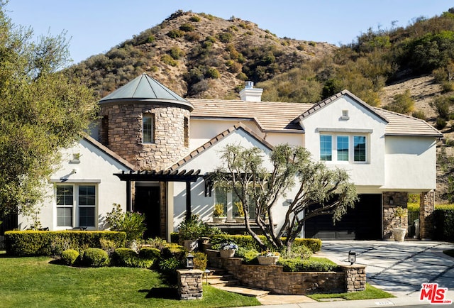 view of front of home featuring a garage, a mountain view, and a front lawn