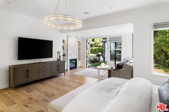 bedroom featuring crown molding, a fireplace, light hardwood / wood-style floors, and access to outside