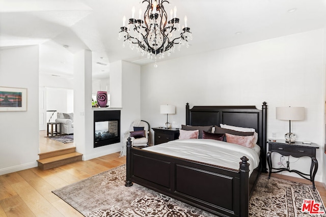 bedroom featuring wood-type flooring and a multi sided fireplace