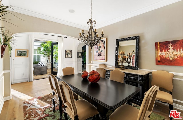 dining area with crown molding, a chandelier, and light wood-type flooring