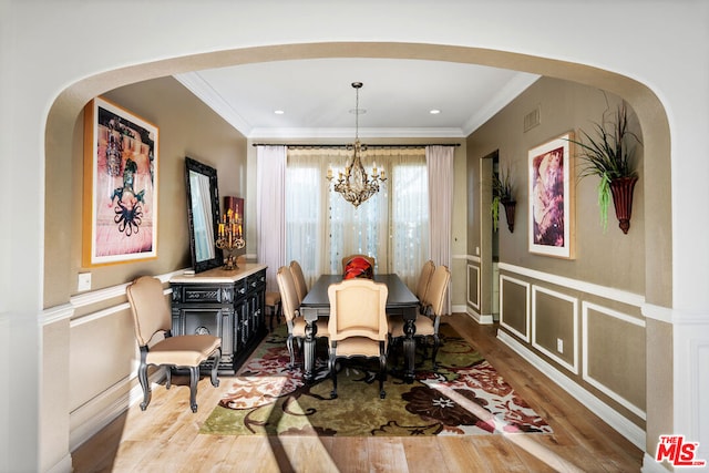 dining room featuring hardwood / wood-style flooring, ornamental molding, and a chandelier