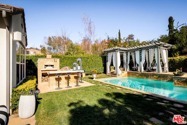 view of pool with a lawn, an outdoor stone fireplace, a pergola, a patio area, and exterior bar