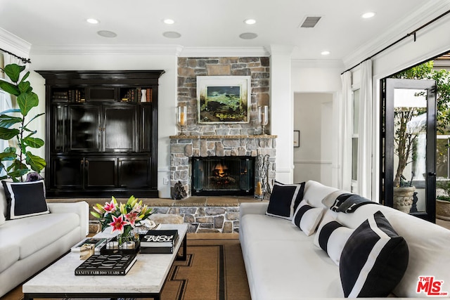 living room with ornamental molding and a stone fireplace