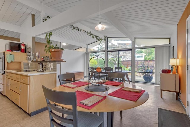 dining room featuring vaulted ceiling with beams and a wall of windows