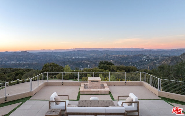 patio terrace at dusk with an outdoor living space with a fireplace and a mountain view