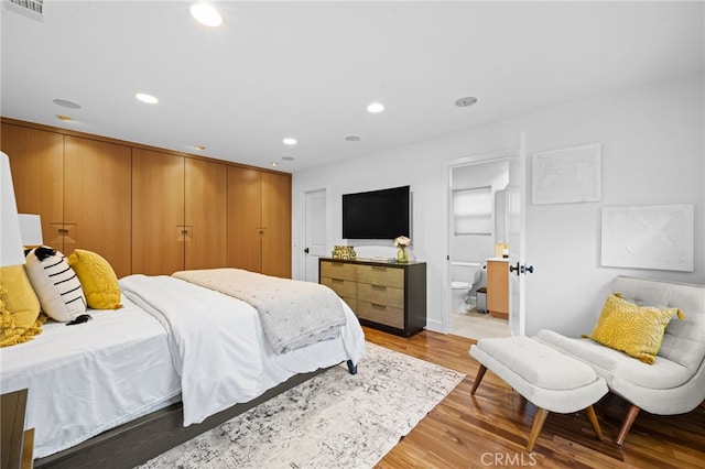 bedroom with light hardwood / wood-style floors and ensuite bath