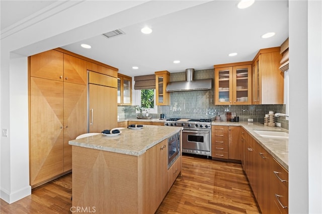 331 Ledroit St, Laguna Beach, CA 92651 - kitchen featuring built in appliances, wall chimney exhaust hood, decorative backsplash, a sink, and wood finished floors