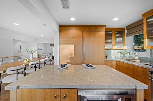 331 Ledroit St, Laguna Beach, CA 92651 - kitchen with glass insert cabinets, a center island, built in fridge, light stone countertops, and visible vents