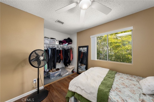 bedroom with ceiling fan, dark wood-type flooring, a closet, and a textured ceiling