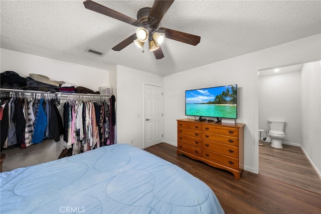 bedroom featuring dark wood-type flooring, ensuite bathroom, a textured ceiling, a closet, and ceiling fan