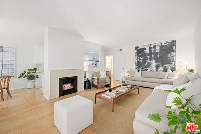 living room featuring a tile fireplace and light hardwood / wood-style floors