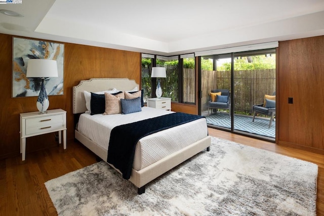 bedroom featuring hardwood / wood-style flooring, wooden walls, and access to outside