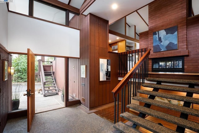 stairway with french doors, wood walls, carpet, and a high ceiling