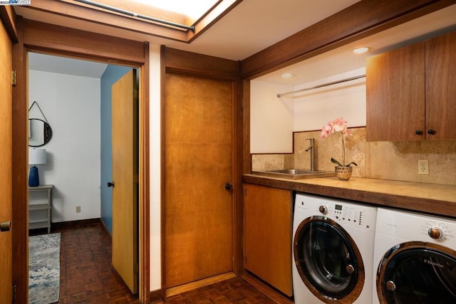 laundry area with dark parquet flooring, sink, and washer and clothes dryer