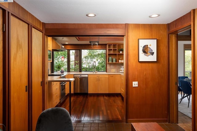 bar featuring sink, dark wood-type flooring, dishwasher, oven, and wood walls