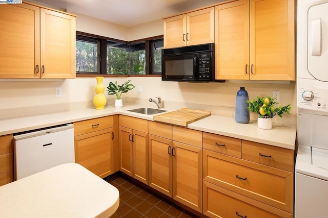 kitchen featuring sink, stacked washer and dryer, dishwasher, dark tile patterned flooring, and light brown cabinets