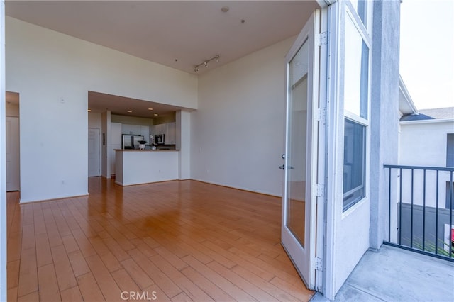 interior space featuring light hardwood / wood-style flooring, rail lighting, and a high ceiling