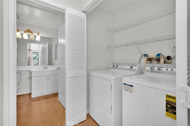 washroom with sink, independent washer and dryer, and light hardwood / wood-style floors