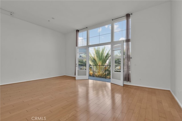 empty room featuring a high ceiling and light wood-type flooring