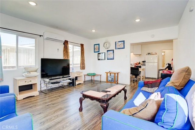 living room with a wall unit AC and light hardwood / wood-style flooring