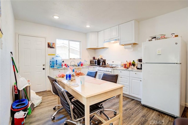 kitchen featuring wood-type flooring, light stone countertops, white cabinets, and white appliances