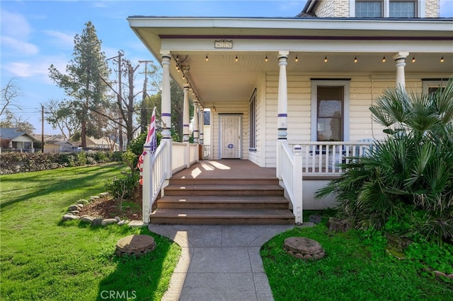 entrance to property featuring a yard and covered porch